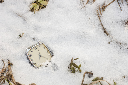 old wristwatch lying in the snow in the winterの写真素材