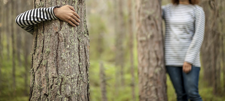 panorama of two girls in striped clothes hugging tree trunks in a summer forestの写真素材