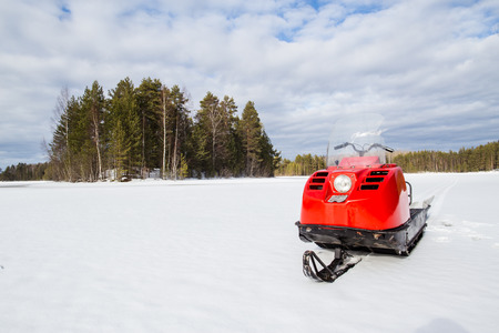 snowmobile with is on the lake, around the snowy forest in sunny weatherの写真素材