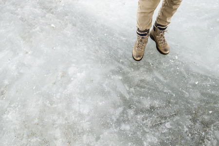 human legs dressed in hiking boots standing on ice