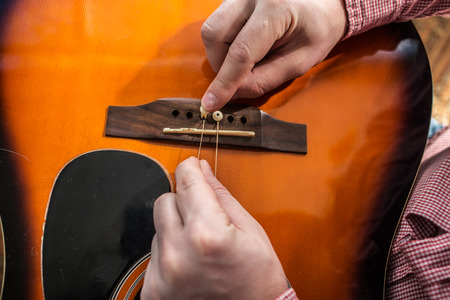 man changes hands old ripped guitar strings on the acoustic guitar on the new