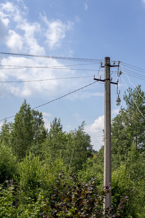 electric pole on the background of trees and blue sky with cloudsの写真素材