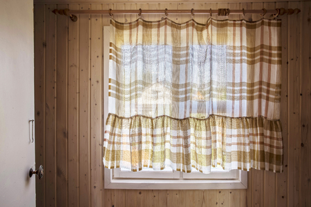 Rustic window from inside the house, closed by curtains, through which visible nature, the neighboring houses and the sky.の写真素材