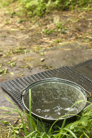 metallic bucket with pure drinking water stands on the footpath in the kitchen garden the background wicket and a fenceの写真素材