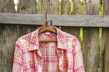 Shirt hangs a on hanger on the old fence of outdoors the boards in a villageの写真素材