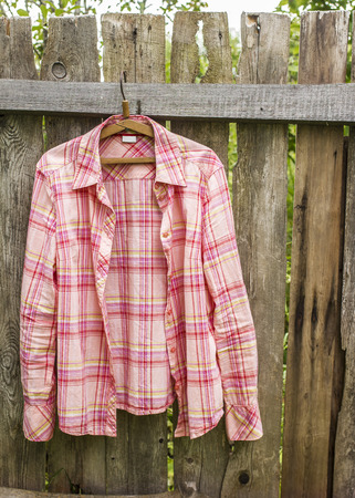 Shirt hangs a on hanger on the old fence of outdoors the boards in a villageの写真素材