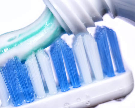 Macro blue toothbrush coated striped toothpaste on a white backgroundの写真素材