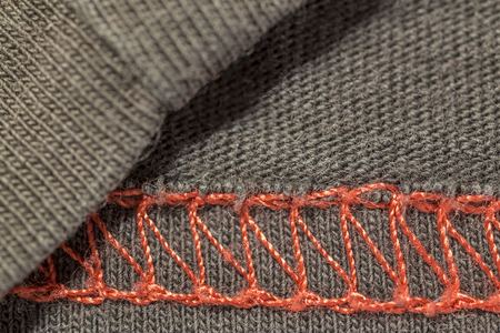 closeup macro red overlock seam on a brown T-shirt fabricの写真素材