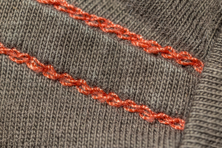 closeup macro red seam on a brown T-shirt fabricの写真素材