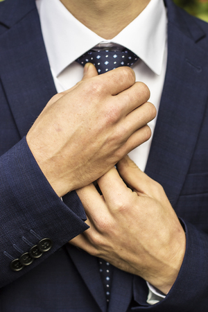The groom corrects his tie their own hands close upの写真素材