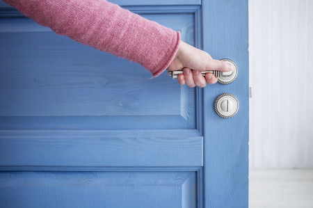 man holding a metal pen in an open wooden door blueの写真素材
