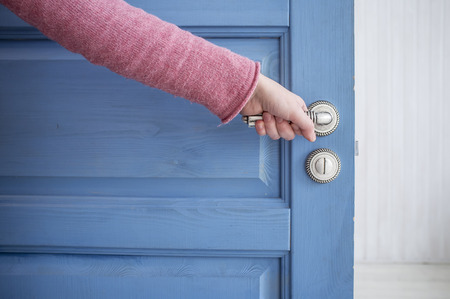 man holding a metal pen in an open wooden door blueの写真素材