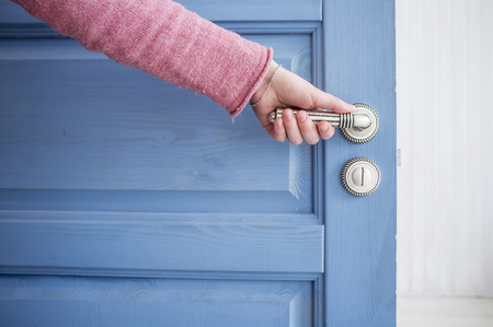 man holding a metal pen in an open wooden door blueの写真素材