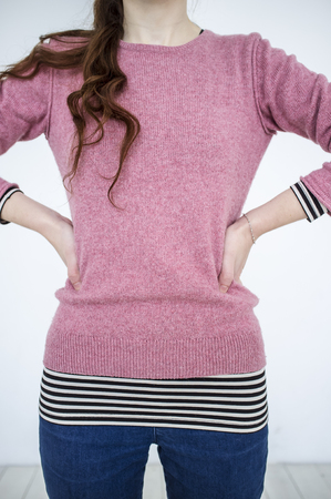 Slim young girl standing with arms akimbo on a white backgroundの写真素材