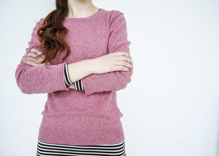 Slim young girl standing arms crossed on white backgroundの写真素材
