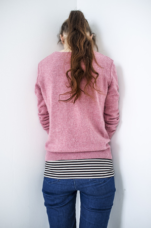 Elegant sad girl standing in a corner of the room with a lowered headの写真素材
