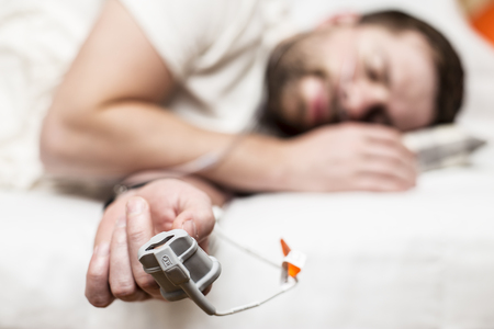 Sleep Apnea Diagnostic medical device Kit attached to the finger and the human nose, which lies in bedの写真素材