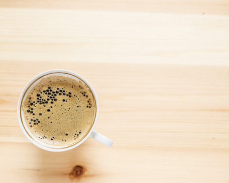 Appetizing cup of coffee with foam on the wooden tableの写真素材