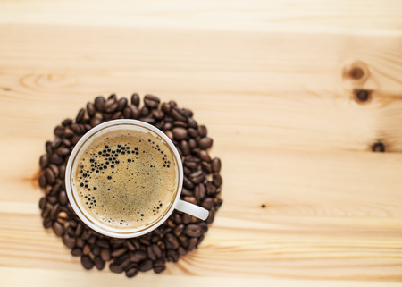 Appetizing cup of coffee and grain lying on the wooden tableの写真素材