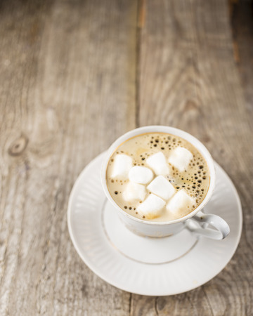 Hot black coffee in a cup with marshmallows on the old a wooden tableの写真素材