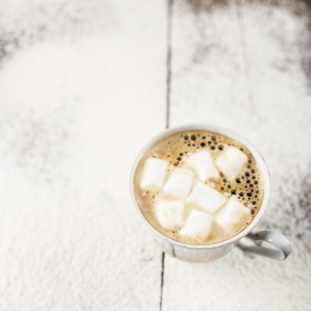 Hot black coffee in a cup with marshmallows on the old a wooden table sprinkle with powdered sugarの写真素材