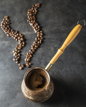 Hot aromatic coffee in cuzve on a table and pairs of grains close upの写真素材