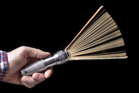enlightenment concept of an open book and a flashlight in the hand of manの写真素材
