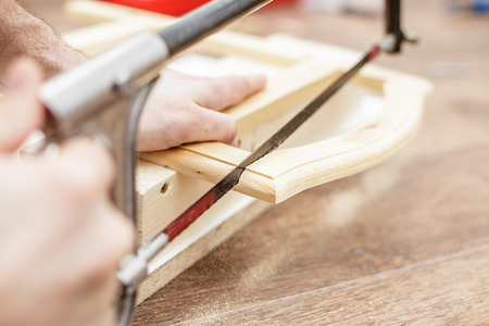 Man sawing a board with a hand saw wood, close-up