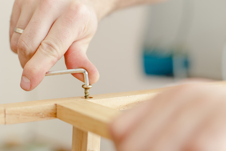 Man assembling of wooden furniture with the use of tools, close-upの写真素材