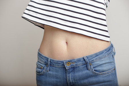 girl in blue jeans and a striped sweater and lifted her arms bared belly with a beautiful waist and...