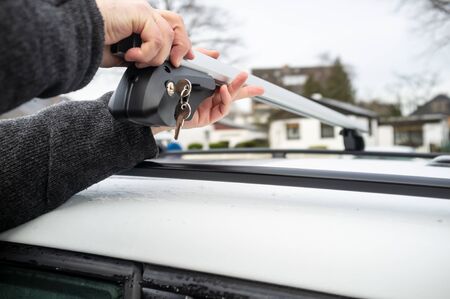 Man installs attachments with a lock and keys for the trunk or cargo box on the roof of a car.の写真素材