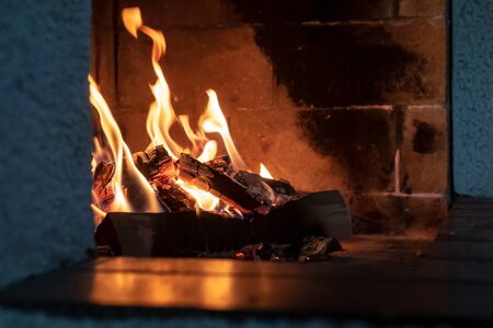 Open fireplace, firewood and fire, giving heat, on a cold winter evening, in a cozy house.の写真素材