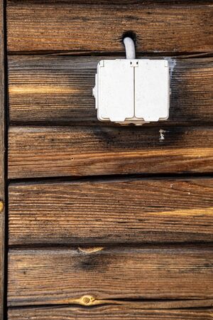 Waterproof electrical outlet with a closed lid, on the log wall of the house, outdoors.の写真素材
