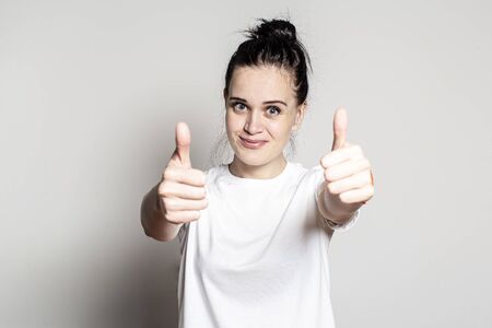 Positive young woman showing a big hand thumbs up gesture, smiling and looking at the camera. Concept of approval and success.の写真素材