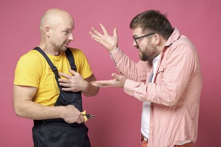 An angry client gesticulates with hands, swears and shouts at the worker, who innocently looks at him and makes excuses.の写真素材
