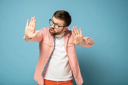 Man reassures someone by making a stop gesture with hand, holding palms forward and looking...