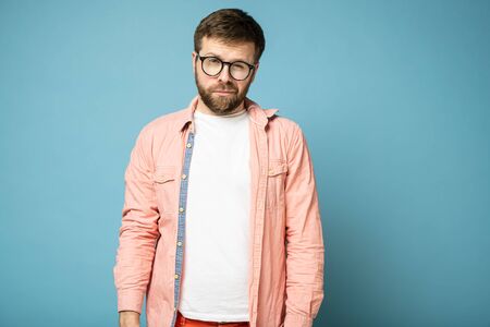 Handsome, calm, bearded man with glasses narrowed eyes and looks at the camera suspiciously.の写真素材