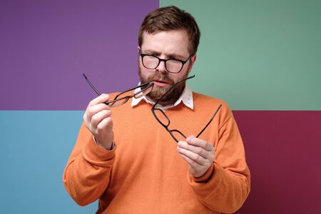 Bearded man in bewilderment and stupor, he selects and compares glasses, he has to solve a difficult...