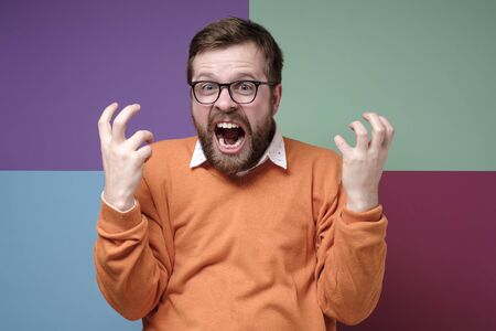 Angry bearded man screams violently, furious squeezes hands and looks at the camera.の写真素材