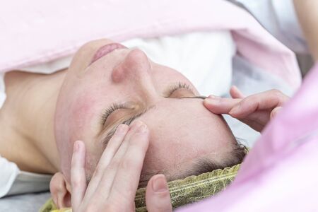 Professional beautician massaging with his hands applies a cosmetic, relaxing mask to the face after chemical peeling.の写真素材