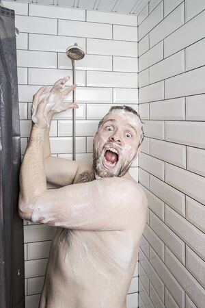 Shocked man in soapy foam screams and asks for help, because the soul has run out of water or something has broken.の写真素材