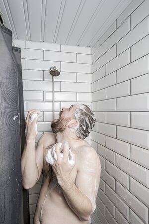 Fat man in soapy foam is frightened and screams, because the soul has run out of water or something has broken.の写真素材