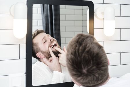 Man looks in the mirror, he opened mouth and examines the absence of a tooth that the dentist recently removed.の写真素材