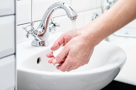 Washing hands with soap, under running water, in the bathroom.の写真素材