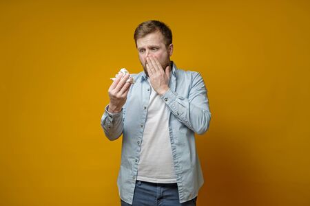 Caucasian man with a runny nose scaredly looks at his handkerchief. Concept of the spread of the virus.の写真素材