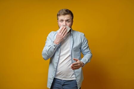 Man is about to cough or sneeze and scared covers mouth with a napkin. Concept of the spread of the virus.の写真素材