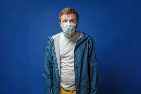 Shocked man in a medical mask, made big eyes and looks fearfully at the camera. Concept of the spread of the virus.の写真素材
