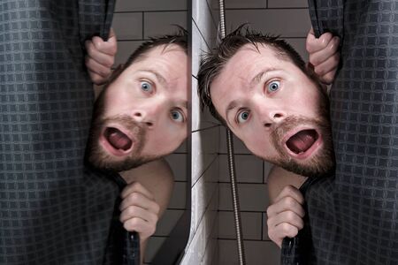 Male head is reflected in the mirror, peeking out from behind the curtains, in the shower with a grimace of horror on his face.の写真素材