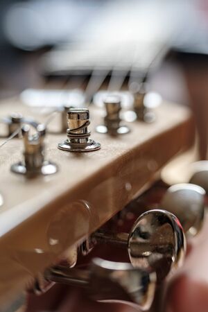 String wound on a peg, close-up, on the headstock of an old wooden guitar, in natural light. Tuning mechanisms for stringed instruments..の写真素材