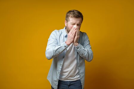 Man is sick, has a runny nose, he coughs or sneezes, covering mouth with a handkerchief. Concept of the spread of the virus.の写真素材